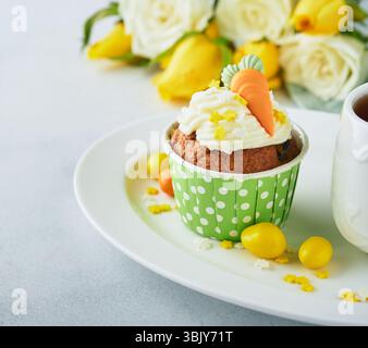 Carrot cake cupcakes for Easter. Carrot cupcakes with cream cheese frosting decorated with tiny marzipan carrots on white backgr Stock Photo