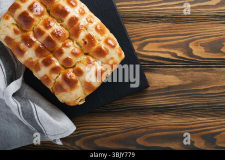 Easter hot cross buns with colored eggs Easter gingerbread rabbits and cookies over dark brown plank wooden old table background Stock Photo