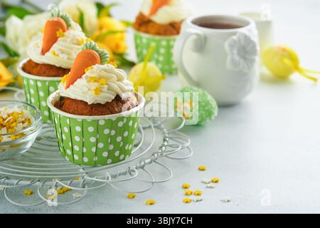 Carrot cake cupcakes for Easter. Carrot cupcakes with cream cheese frosting decorated with tiny marzipan carrots on white backgr Stock Photo