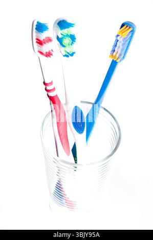colorful toothbrushes in a glass over white Stock Photo