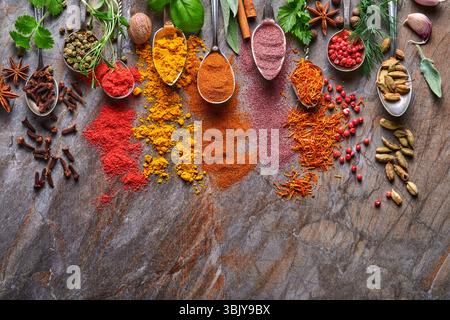 Various colorful herbs and spices in spoons for cooking: turmeric, dill, paprika, cinnamon, saffron, basil and rosemary. Indian Stock Photo