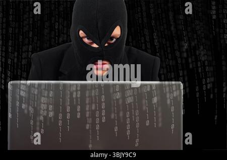 A hacker with a laptop against binary background Stock Photo