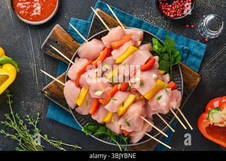 Raw shish kebab on wooden board, spices, herbs and vegetables on dark grey background. Barbecue Raw ingredients for goulash or s Stock Photo