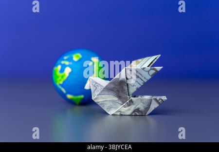 An origami bird folded from a US dollar bill and a globe. Global finance, international trade, and the worldwide movement of money. Stock Photo
