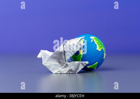 An origami bird folded from a US dollar bill and a globe. Global finance, international trade, and the worldwide movement of money. Stock Photo