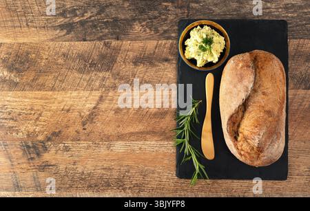 Freshly baked bread and rustic handmade herbs butter on the table. Stock Photo