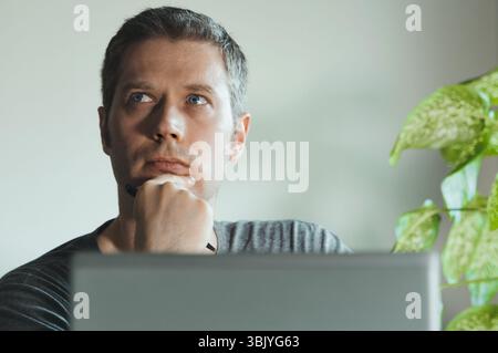 Thoughtful handsome man in front of his laptop in the office. Stock Photo