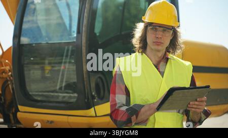 Excavator operator in hard hat using tablet pc. Stock Photo