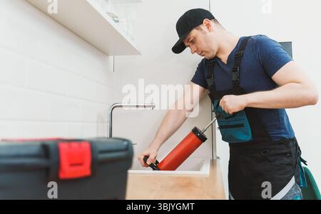Plumber unclogging kitchen sink with professional force pump cleaner. Stock Photo