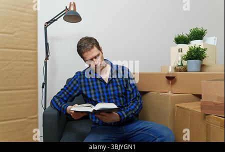 Handsome man reading book in new apartment. Stock Photo
