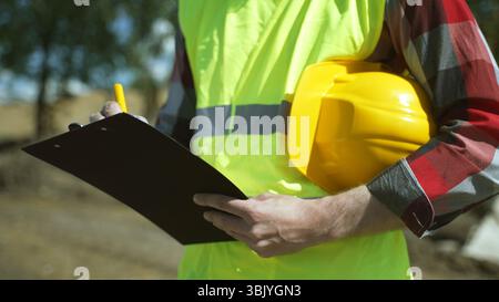 Builder with hard hat inspects construction site. Close-up. Stock Photo