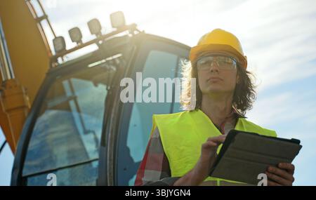 Excavator operator in hard hat using tablet pc. Stock Photo