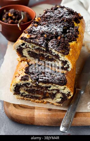 Honey roll with poppy seeds and raisins on a gray concrete background. Selective focus Stock Photo