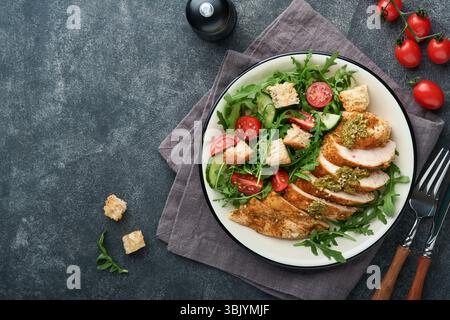Fresh salad with grilled chicken fillet, lettuce, arugula, spinach, tomatoes, cucumber and pesto sauce, sesame seeds with olive Stock Photo