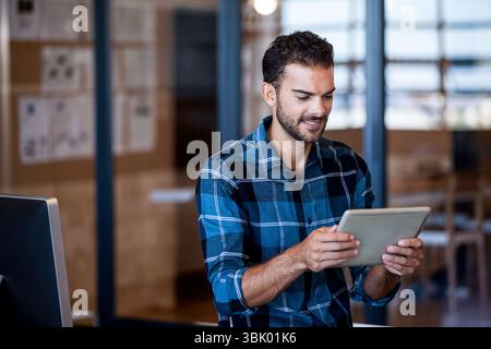 Monitor glowing on office desk behind glass partition displaying cork board with pinned papers Stock Photo