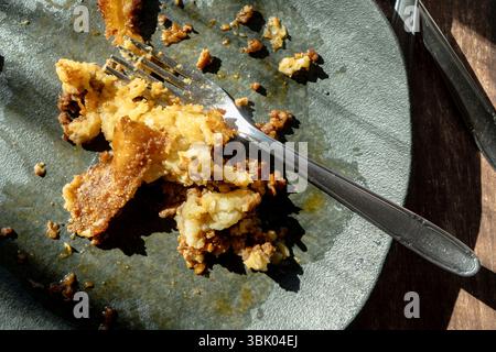 A dirty plate with the remains of a slice of shepherd's pie or meat pie after eating. Stock Photo