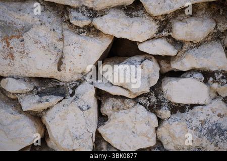 Natural stone wall in a village in Crete, Greece. Irregularly shaped stones of varying sizes form a traditional dry-stone wall Stock Photo