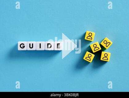 Leadership and guidance concept. Guiding arrow pointing at group of cubes showing people symbols on blue background. Stock Photo