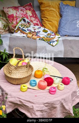 Close-up of a small garden table with embroidery supplies on a warm summer day. Colorful threads, needles, fabric, scissors, and a wooden hoop Stock Photo