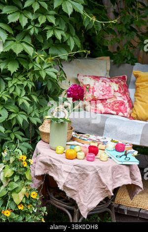 Close-up of a small garden table with embroidery supplies on a warm summer day. Colorful threads, needles, fabric, scissors, and a wooden hoop Stock Photo