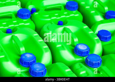 Green plastic jars with blue lids for storing chemical liquids and fuels and lubricants, close-up. Stock Photo