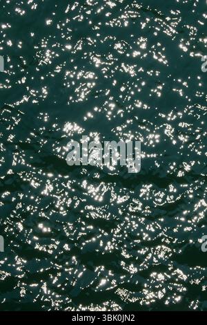 Water surface high contrast top view. Sun glare on water. Background abstracted wallpaper texture. Stock Photo