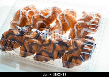 White and black chocolate mini croissants sold in plastic croissant containers on white background Stock Photo