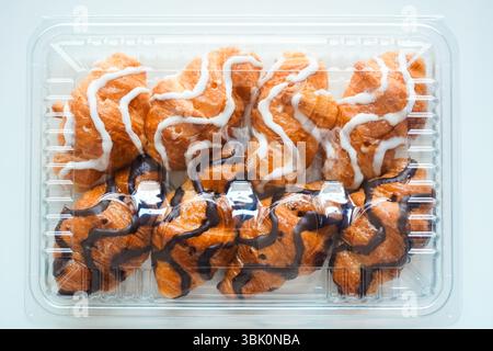 White and black chocolate mini croissants sold in plastic croissant containers on white background Stock Photo