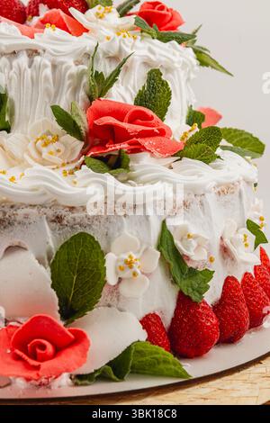 A multi-layered cake showcases vibrant flowers, fresh strawberries, and mint leaves. Perfect for celebrations, it adds elegance to any dessert table. Stock Photo