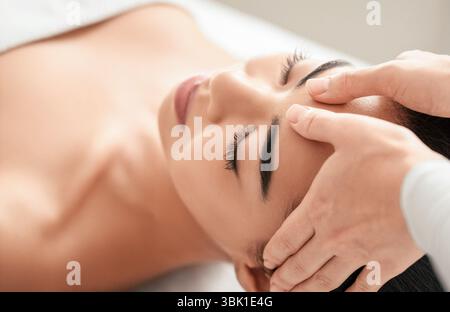 Spa therapist making relaxing head massage for beautiful asian woman in salon Stock Photo