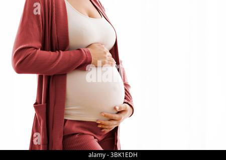 Motherhood Concept. Cropped Image Of Young Pregnant Woman Tenderly Embracing Her Tummy Stock Photo