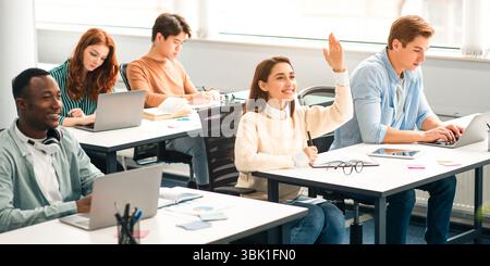 Portrait of smiling female student raising hand at classroom Stock Photo