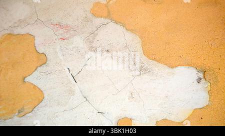 Cracked and Peeling Yellow Wall Texture with Exposed Plaster Stock Photo