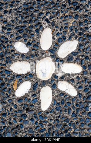 Black and white photo of a stone path with a white flower in the middle. The stone path is made of small rocks and the flower is made of larger rocks. Stock Photo