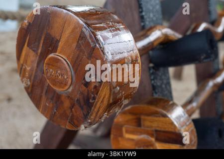 Wooden rack of dumbbells is on a sandy beach. The dumbbells are wooden and are stacked on top of each other Stock Photo