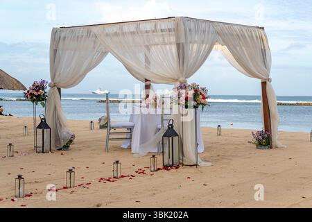 Beach wedding with a white tent and a table with two chairs. The chairs are facing the ocean Stock Photo