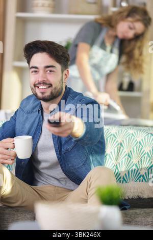 husband watching tv while wife ironing Stock Photo - Alamy