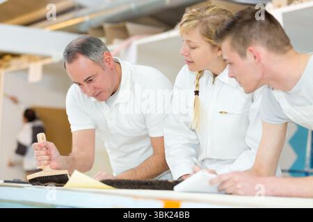 instructor showing apprentices using a brush Stock Photo
