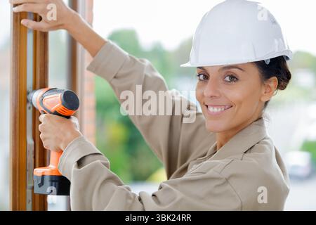 construction worker using cordless screwdriver on window Stock Photo