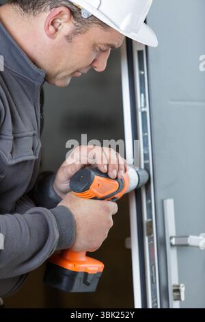 builder wearing protective workwear and holding electric drill Stock Photo