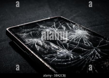 Smartphone with broken screen on dark background Stock Photo