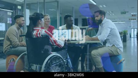 Six office professionals collaborating around meeting table in office, with laptop and wheelchair Stock Photo