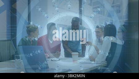 Discussing six professionals leaning over documents in office, with laptop, coffee and tech overlay Stock Photo