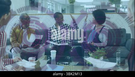 High-fiving two colleagues in checkered shirt and denim overalls at office lounge, with tablet Stock Photo