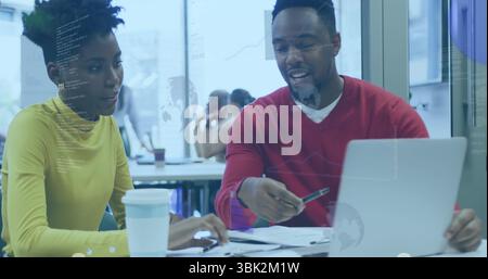 Collaborating coworkers coding on laptop in office and reviewing printed documents with coffee cup Stock Photo