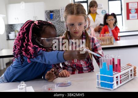Conducting science experiment with test tubes, diverse students engaged in school laboratory Stock Photo