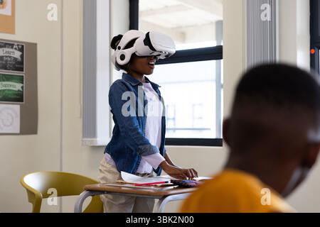 Girl using VR headset in classroom, exploring virtual reality technology, at school Stock Photo