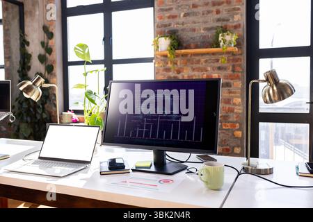 Modern office desk with computer screen displaying coding project and laptop Stock Photo