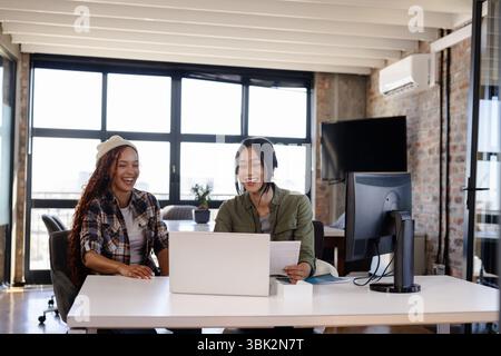 Asian and diverse women collaborating on laptop in modern office Stock Photo