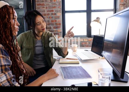 Collaborating on coding project, Asian and diverse women in modern office Stock Photo